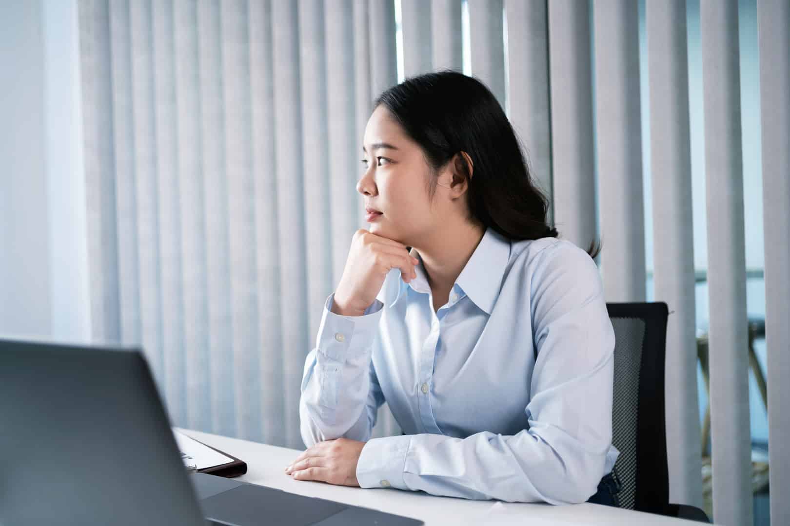 Eine Frau sitzt gelangweilt vor ihrem Computer