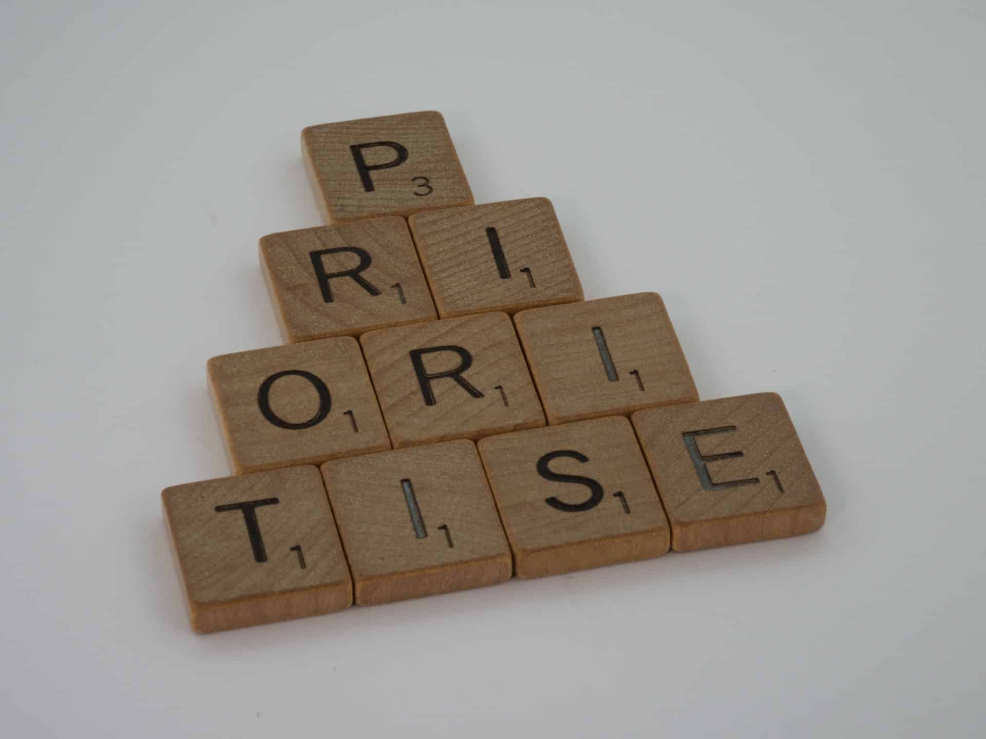 Aus Holzsteine mit aufgedruckten Buchstaben wird das Wort "Prioritise" gelegt