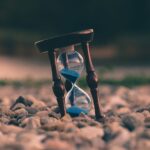 Eine Sanduhr steht im Sand
