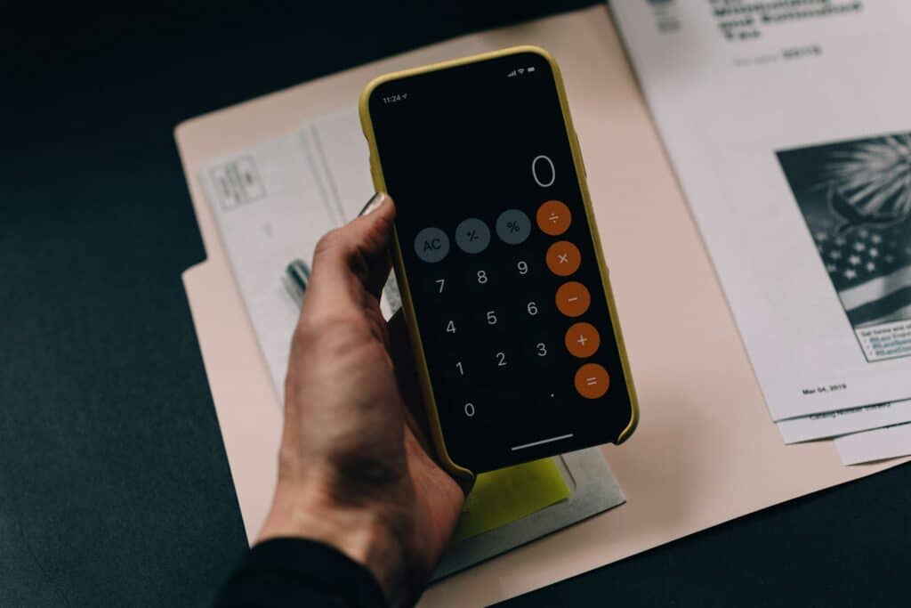 Eine Person hält ein Handy in der Hand, der Taschenrechner ist geöffnet