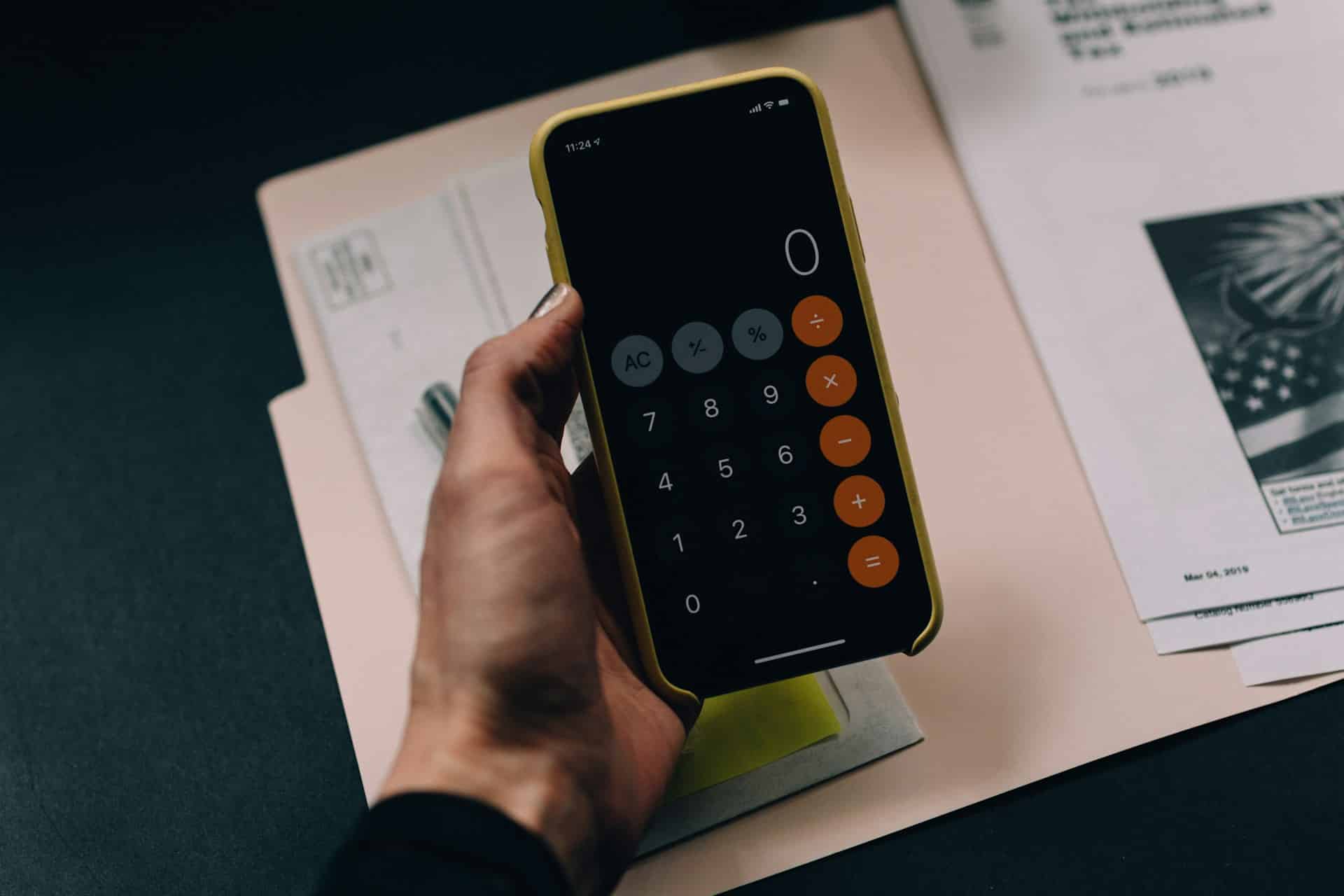 Eine Person hält ein Handy in der Hand, der Taschenrechner ist geöffnet