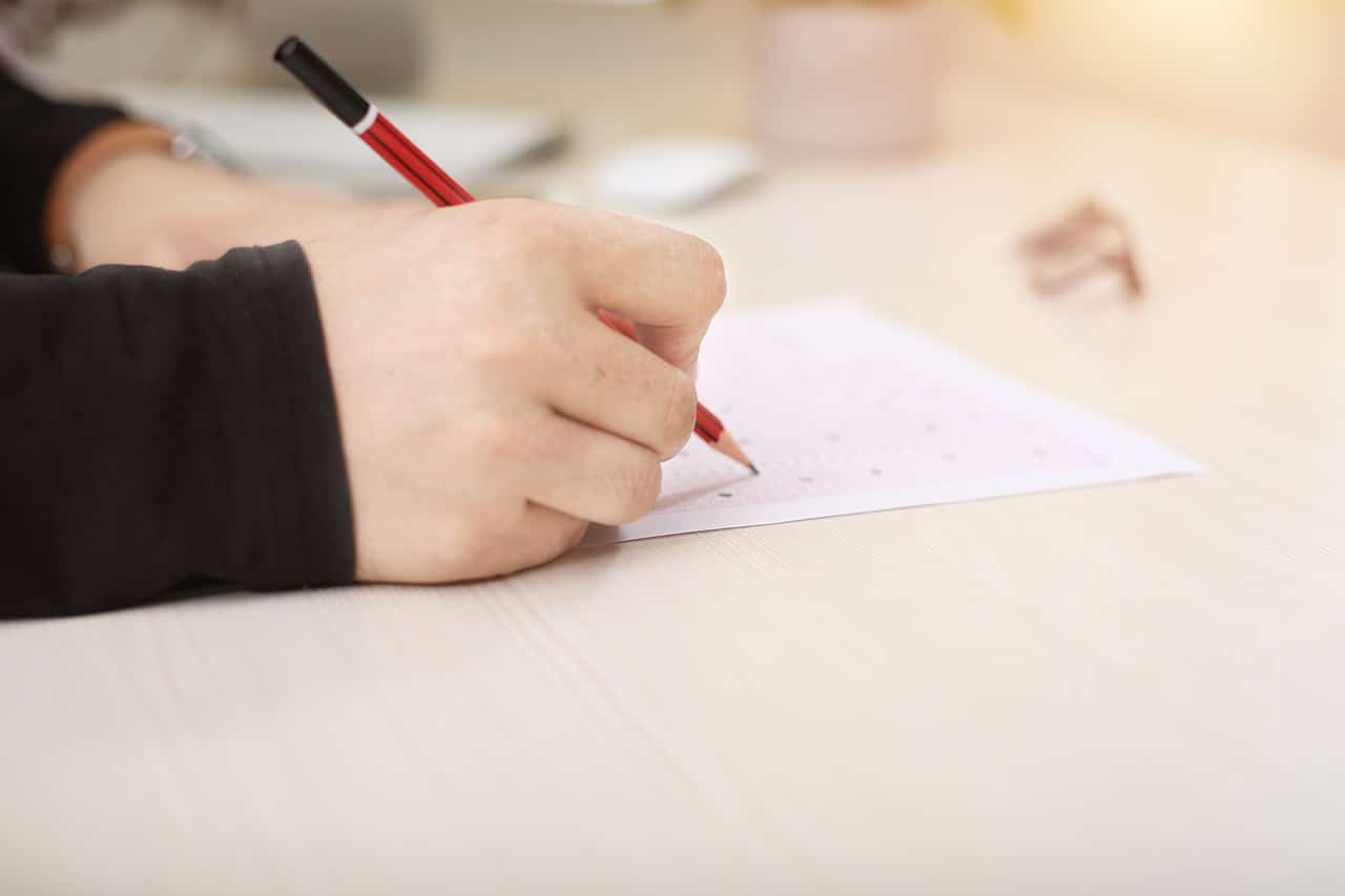 Jemand schreibt einen Test und man sieht die Hand, das Papier und den Stift