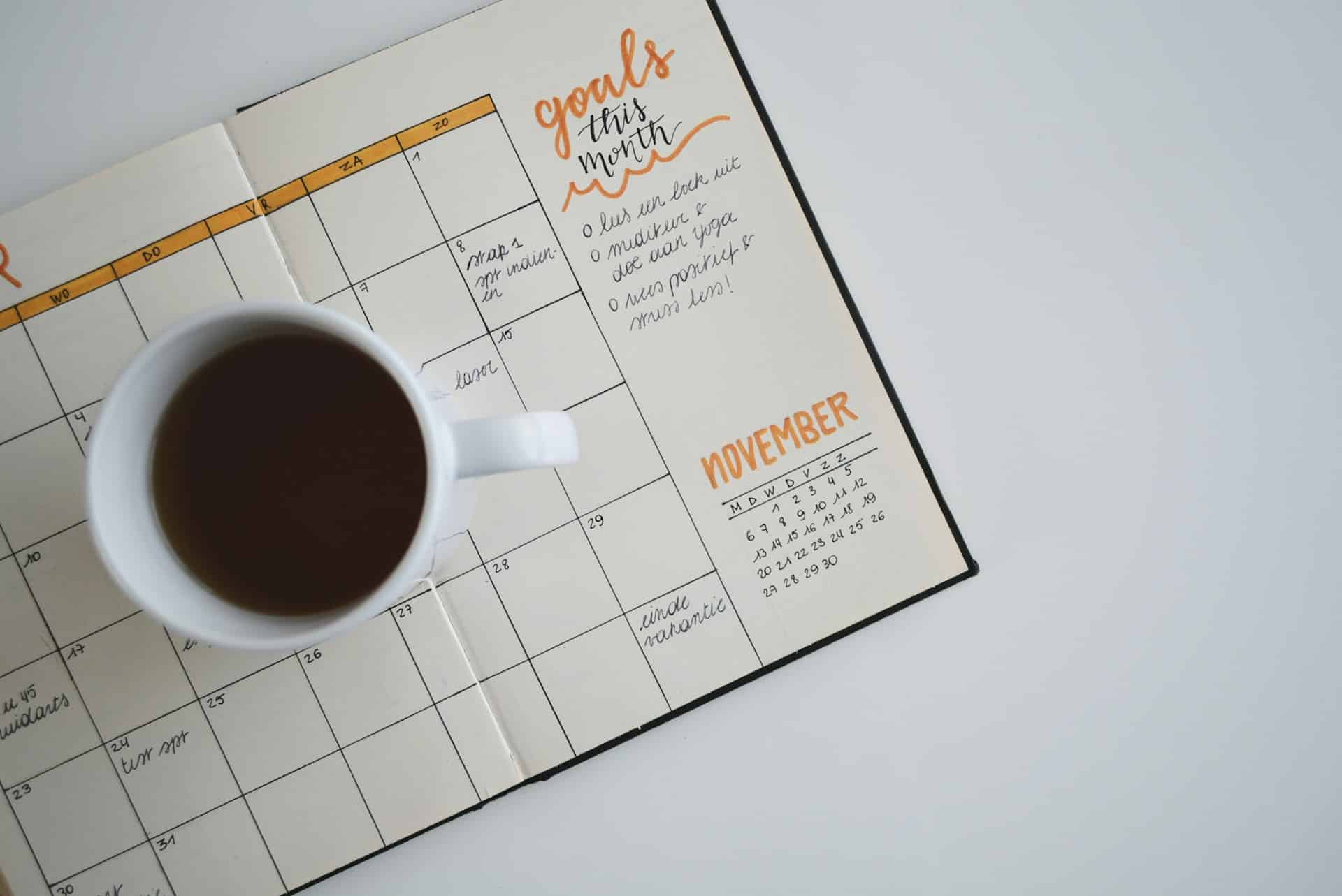 Eine Kaffeetasse steht auf einem aufgeschlagenen Kalender