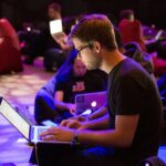 So stärkst Du Deine digitale Kompetenz! Ein Mann sitzt auf einem Stuhl und arbeiten mit einem Laptop